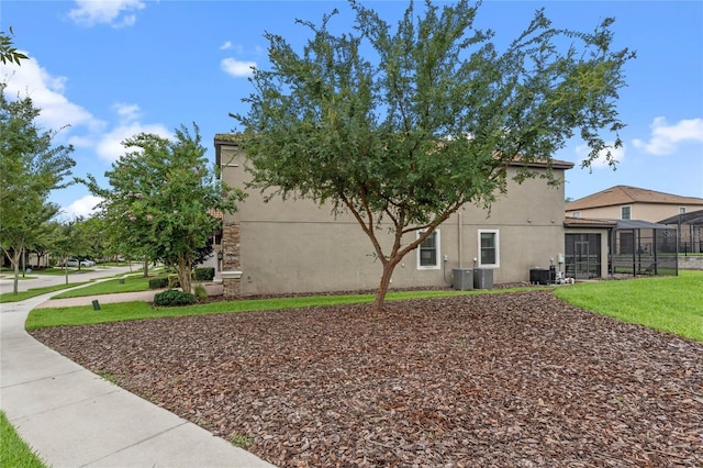 view of side of home featuring a yard, glass enclosure, and cooling unit