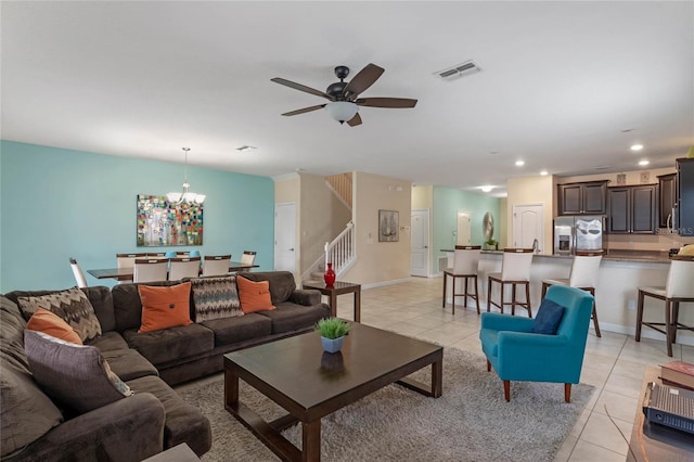 tiled living room with ceiling fan with notable chandelier