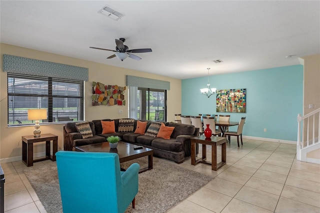 tiled living room with ceiling fan with notable chandelier