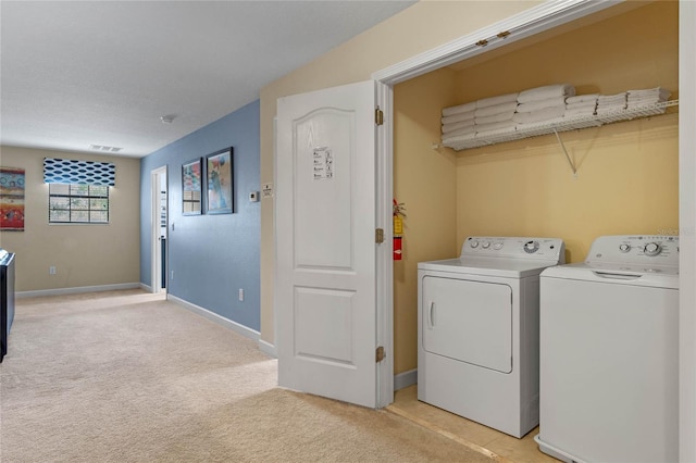 clothes washing area featuring light carpet and independent washer and dryer