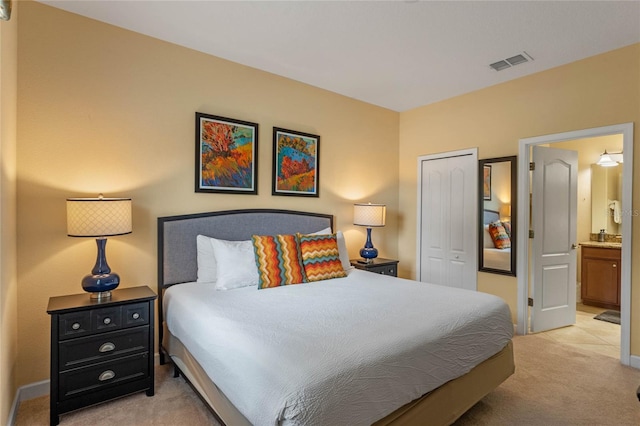 bedroom featuring light colored carpet, ensuite bathroom, and a closet