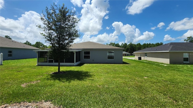 back of house featuring central air condition unit, a yard, and a sunroom