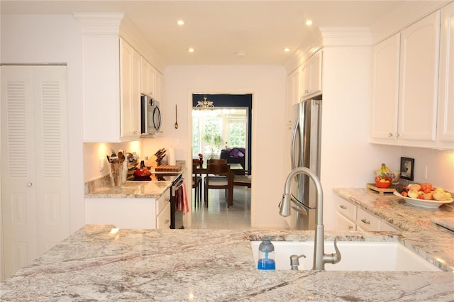 kitchen featuring white cabinets, light stone counters, stainless steel appliances, sink, and kitchen peninsula