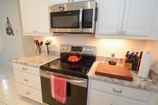 kitchen featuring light stone counters, light tile patterned floors, appliances with stainless steel finishes, and white cabinetry