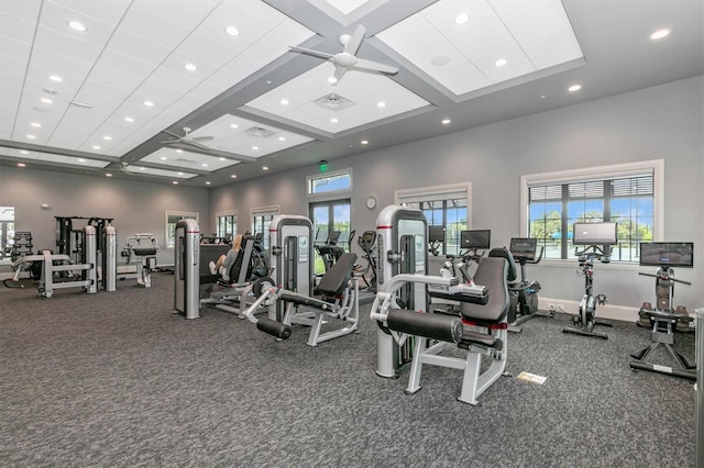 workout area with ceiling fan, a towering ceiling, and coffered ceiling