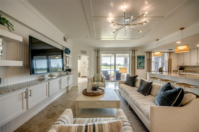 living room featuring crown molding, light tile patterned floors, and a notable chandelier