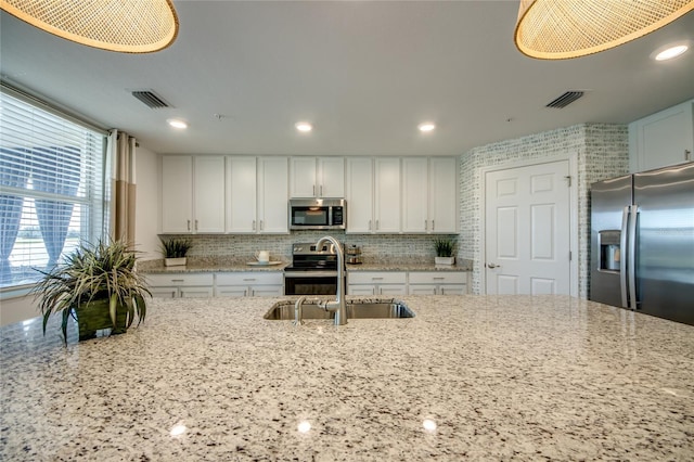 kitchen featuring light stone countertops, sink, tasteful backsplash, white cabinets, and appliances with stainless steel finishes