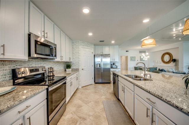 kitchen with white cabinets, hanging light fixtures, sink, decorative backsplash, and appliances with stainless steel finishes