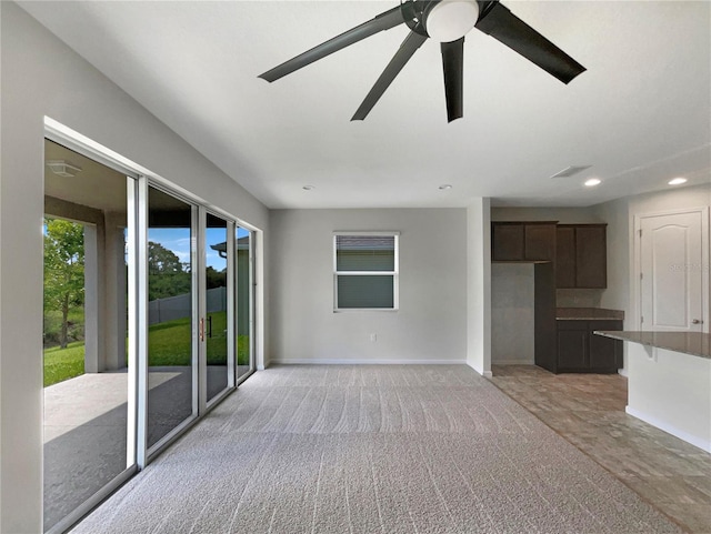 unfurnished living room featuring ceiling fan and light colored carpet