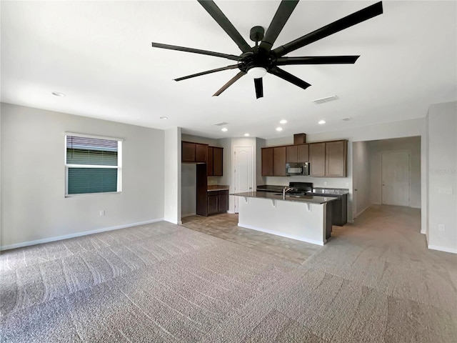 kitchen with sink, a kitchen bar, light carpet, and a center island with sink