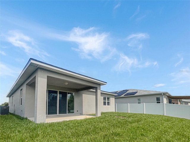 rear view of property with central air condition unit, a yard, and a patio area