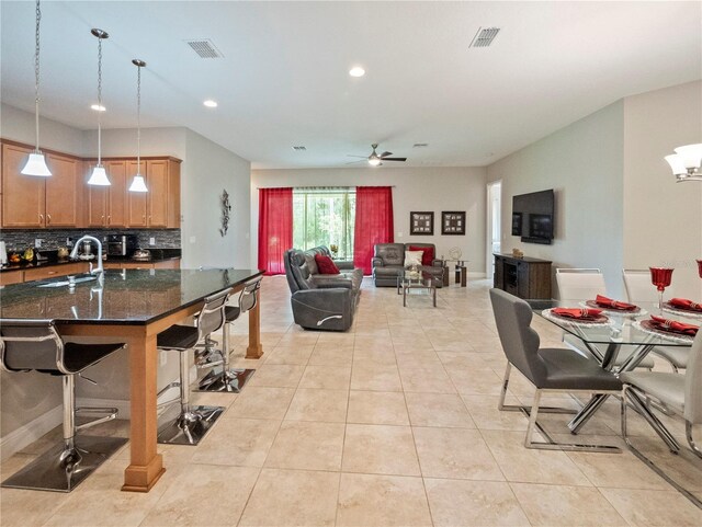 kitchen featuring sink, light tile patterned floors, a kitchen breakfast bar, pendant lighting, and decorative backsplash