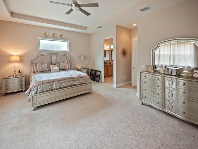 carpeted bedroom featuring ceiling fan, connected bathroom, and a tray ceiling