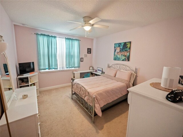 bedroom with ceiling fan, light colored carpet, and a textured ceiling