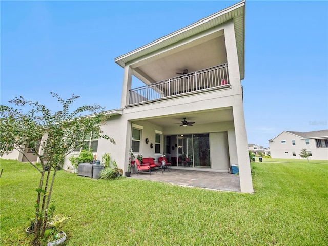 rear view of property featuring ceiling fan, a patio area, a balcony, and a lawn