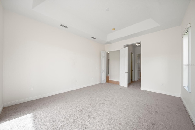 carpeted empty room featuring a tray ceiling