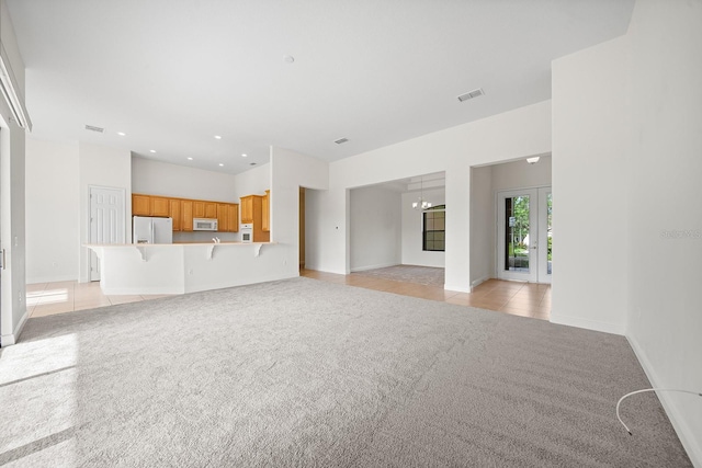 unfurnished living room featuring light tile patterned floors and a chandelier