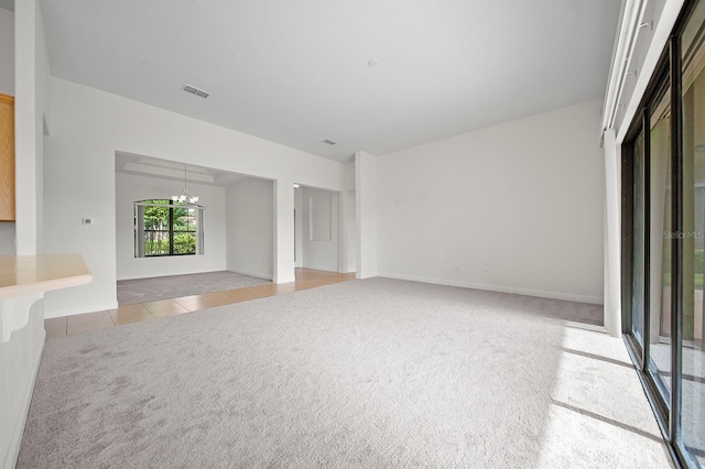 unfurnished living room with an inviting chandelier and light tile patterned floors