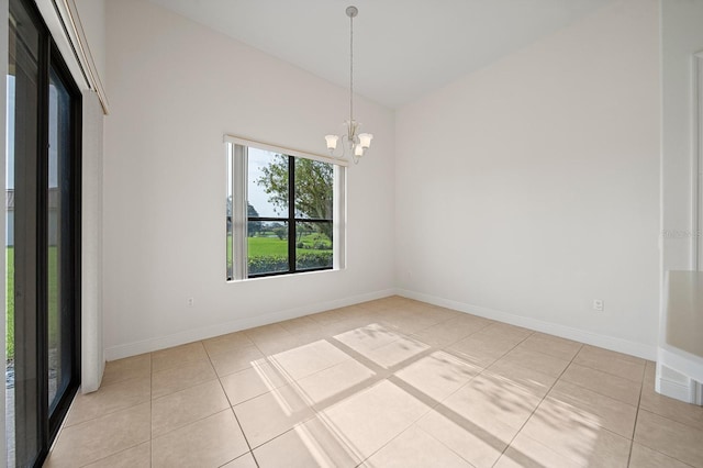 tiled spare room featuring a notable chandelier