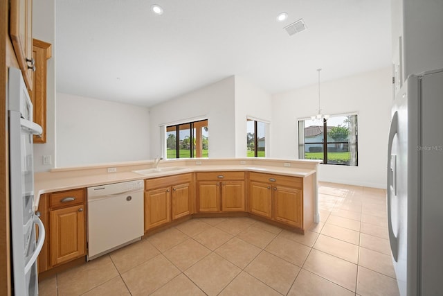 kitchen featuring white appliances, a healthy amount of sunlight, kitchen peninsula, and sink