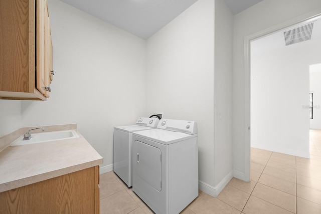 laundry room with cabinets, separate washer and dryer, light tile patterned floors, and sink