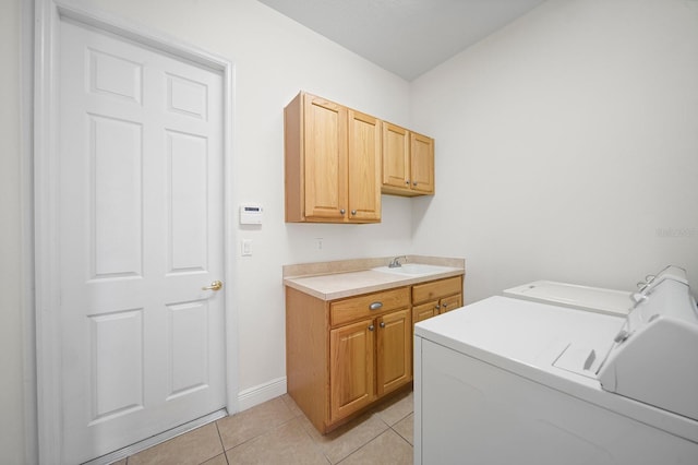 laundry area with sink, washing machine and dryer, light tile patterned flooring, and cabinets