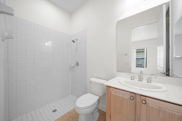 bathroom featuring toilet, vanity, tile patterned floors, and tiled shower