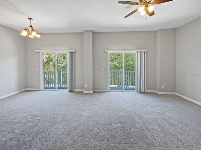 empty room featuring a wealth of natural light, ceiling fan with notable chandelier, and carpet flooring