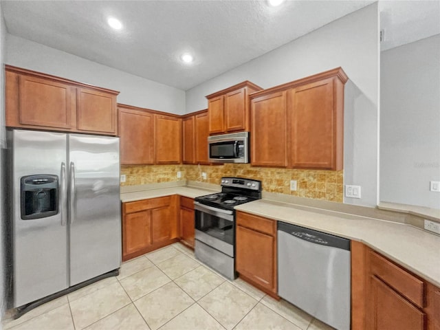 kitchen with appliances with stainless steel finishes, light tile patterned flooring, and backsplash