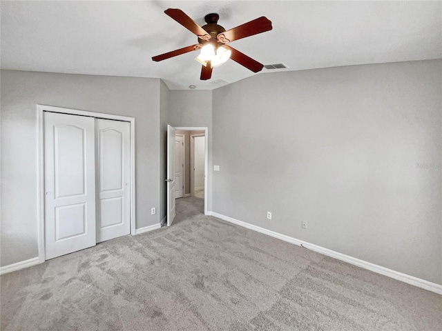 unfurnished bedroom featuring lofted ceiling, a closet, ceiling fan, and light colored carpet