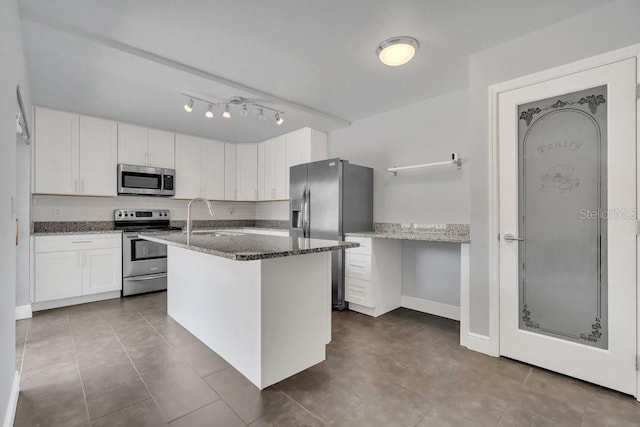 kitchen with sink, white cabinetry, stainless steel appliances, an island with sink, and dark stone counters