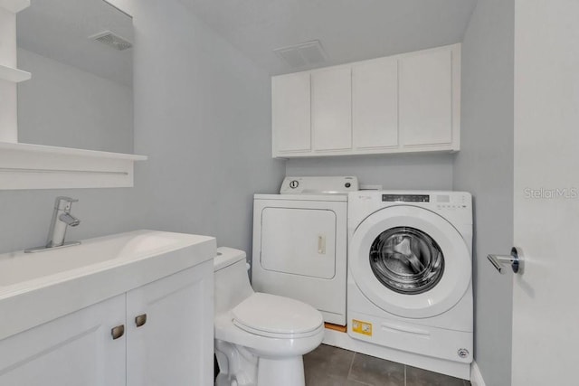 laundry area featuring dark tile patterned flooring, sink, and washing machine and clothes dryer