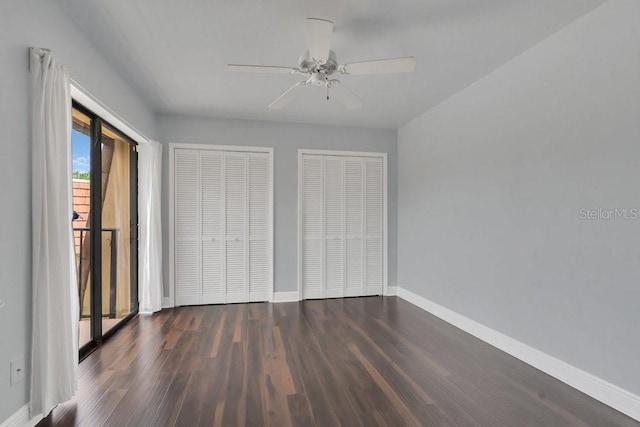 unfurnished bedroom featuring multiple closets, dark hardwood / wood-style floors, and ceiling fan