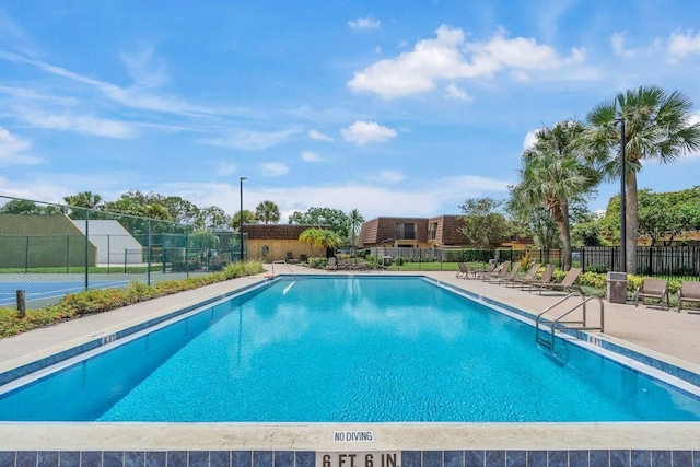 view of swimming pool featuring tennis court