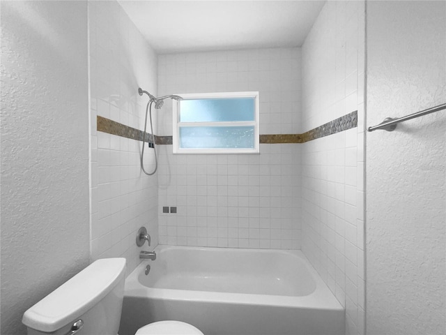 bathroom with toilet and tiled shower / bath