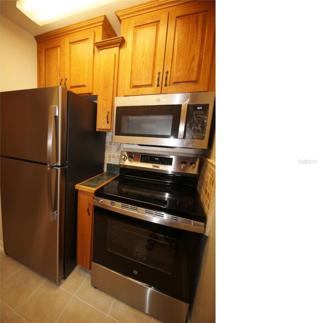 kitchen featuring appliances with stainless steel finishes, light tile patterned floors, and decorative backsplash