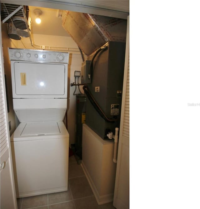 laundry room featuring stacked washing maching and dryer and tile patterned floors