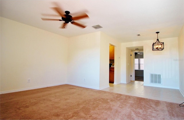 spare room with light carpet and ceiling fan with notable chandelier