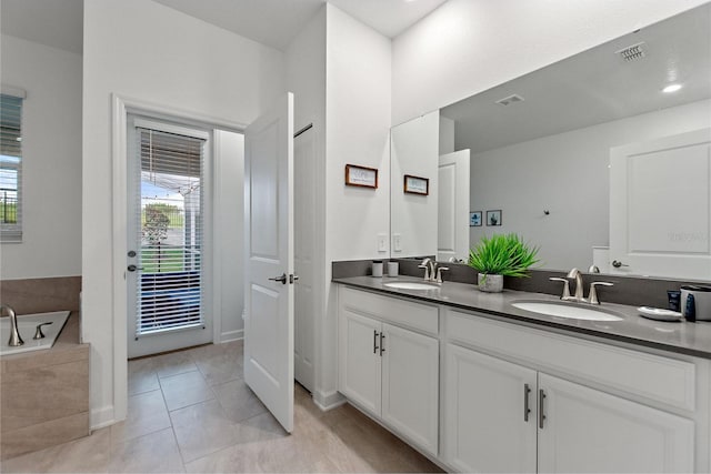 bathroom featuring tile patterned floors, double sink vanity, and a relaxing tiled tub