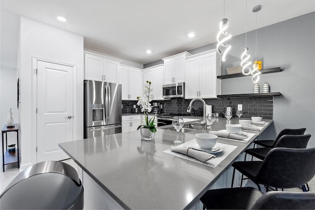 kitchen with stainless steel appliances, pendant lighting, white cabinets, decorative backsplash, and sink