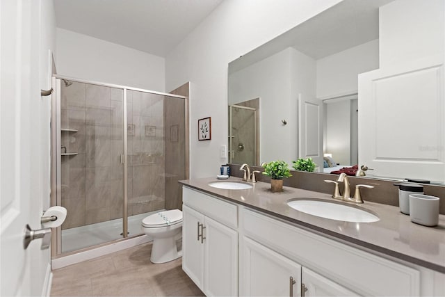 bathroom with tile patterned flooring, a shower with door, toilet, and dual bowl vanity