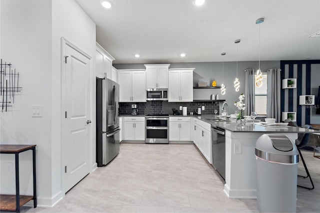 kitchen with appliances with stainless steel finishes, white cabinets, hanging light fixtures, light tile patterned floors, and decorative backsplash