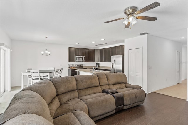 living room with ceiling fan with notable chandelier, sink, and hardwood / wood-style floors