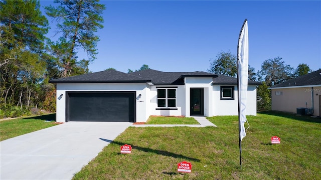 view of front of property featuring a garage, central AC unit, and a front lawn