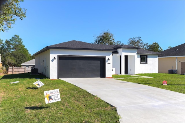 view of front of house with a garage, central AC, and a front lawn