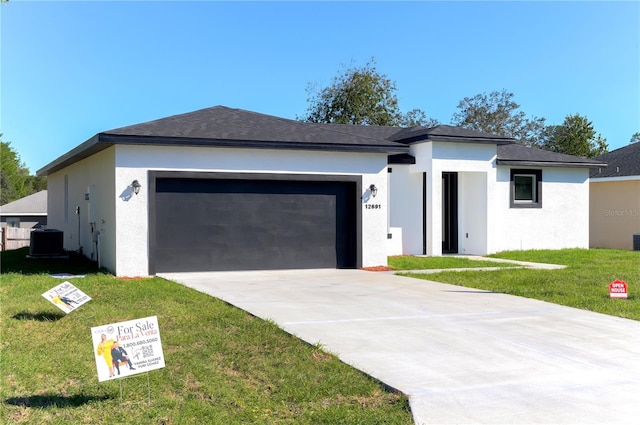 view of front of home with a garage, central AC, and a front lawn