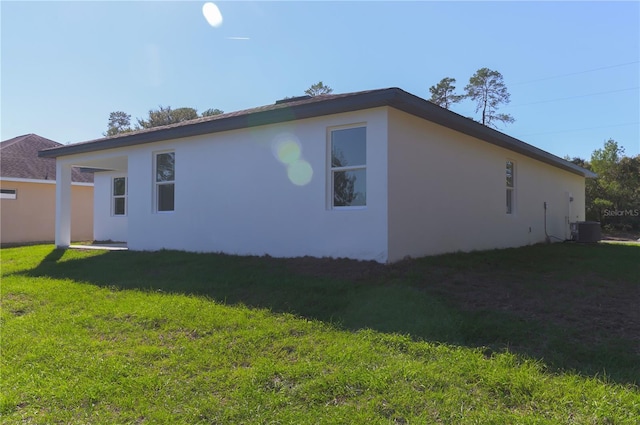 view of side of home featuring a yard and central AC unit