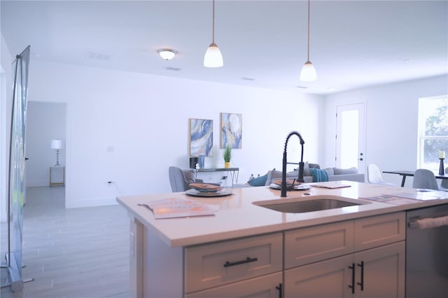 kitchen featuring dishwasher, sink, a kitchen island with sink, and pendant lighting