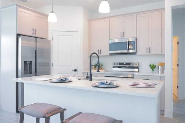 kitchen featuring pendant lighting, sink, a breakfast bar, stainless steel appliances, and an island with sink