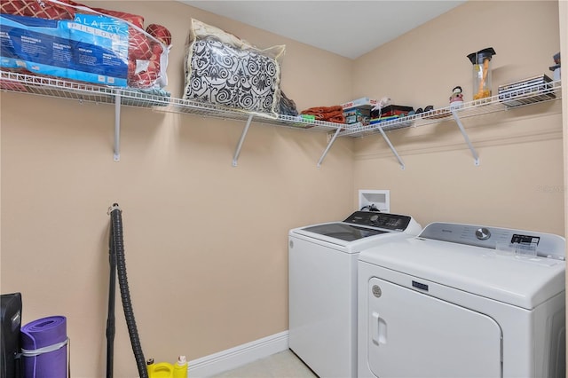 clothes washing area with laundry area, baseboards, and washer and clothes dryer